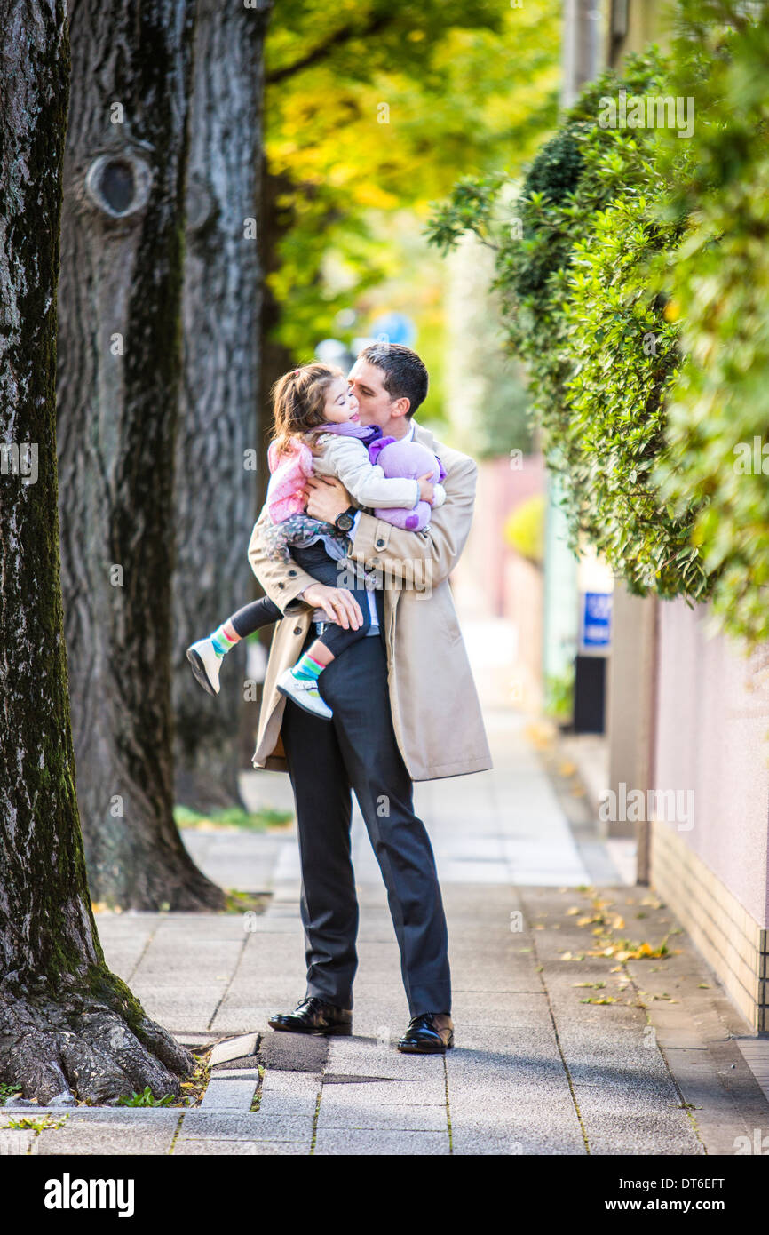 Father carrying daughter on pavement Stock Photo