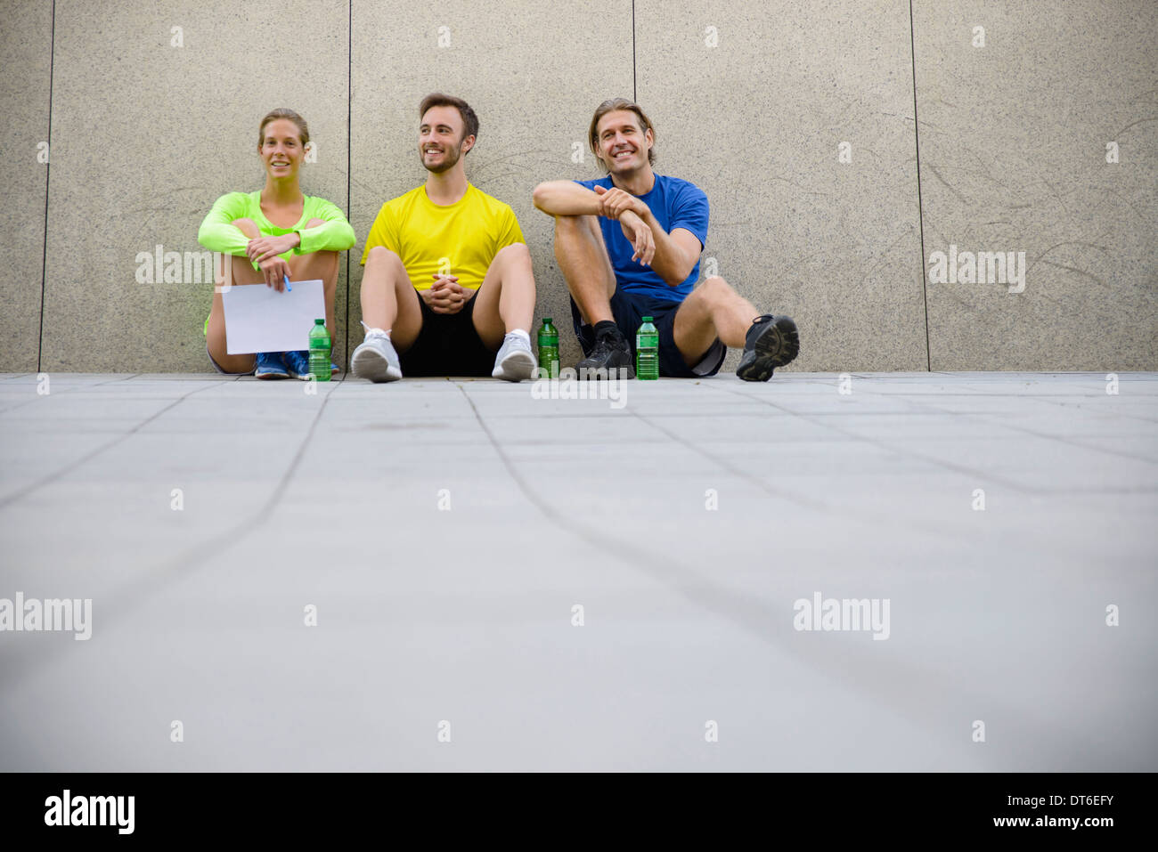 Three friends sitting on floor wearing sports clothing Stock Photo