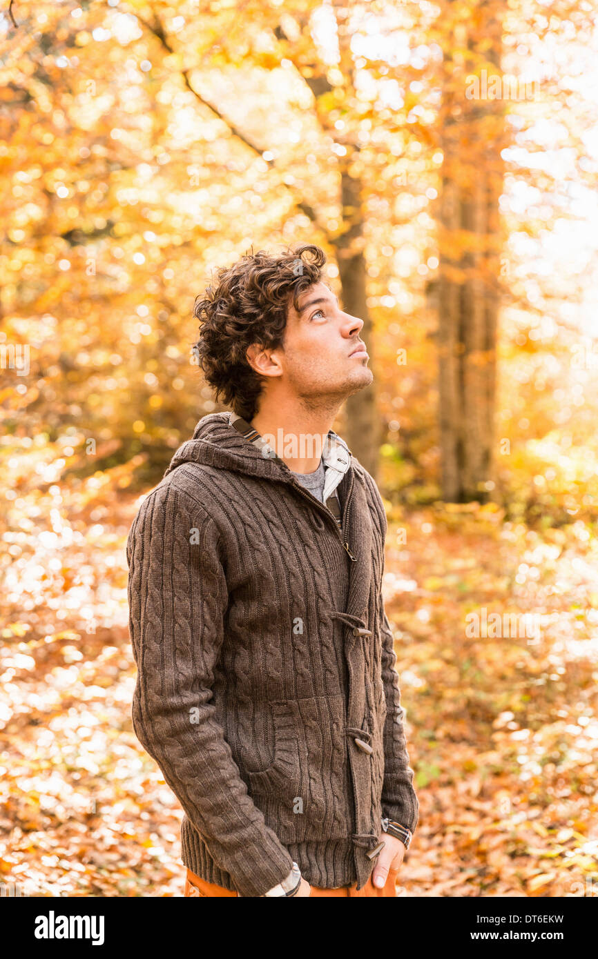 Portrait of man wearing cardigan in forest looking up Stock Photo