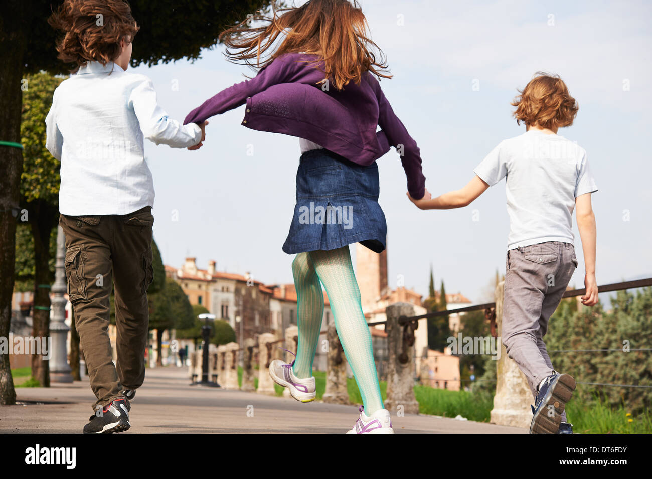 Young boys and older sister marching through park, Province of Venice, Italy Stock Photo