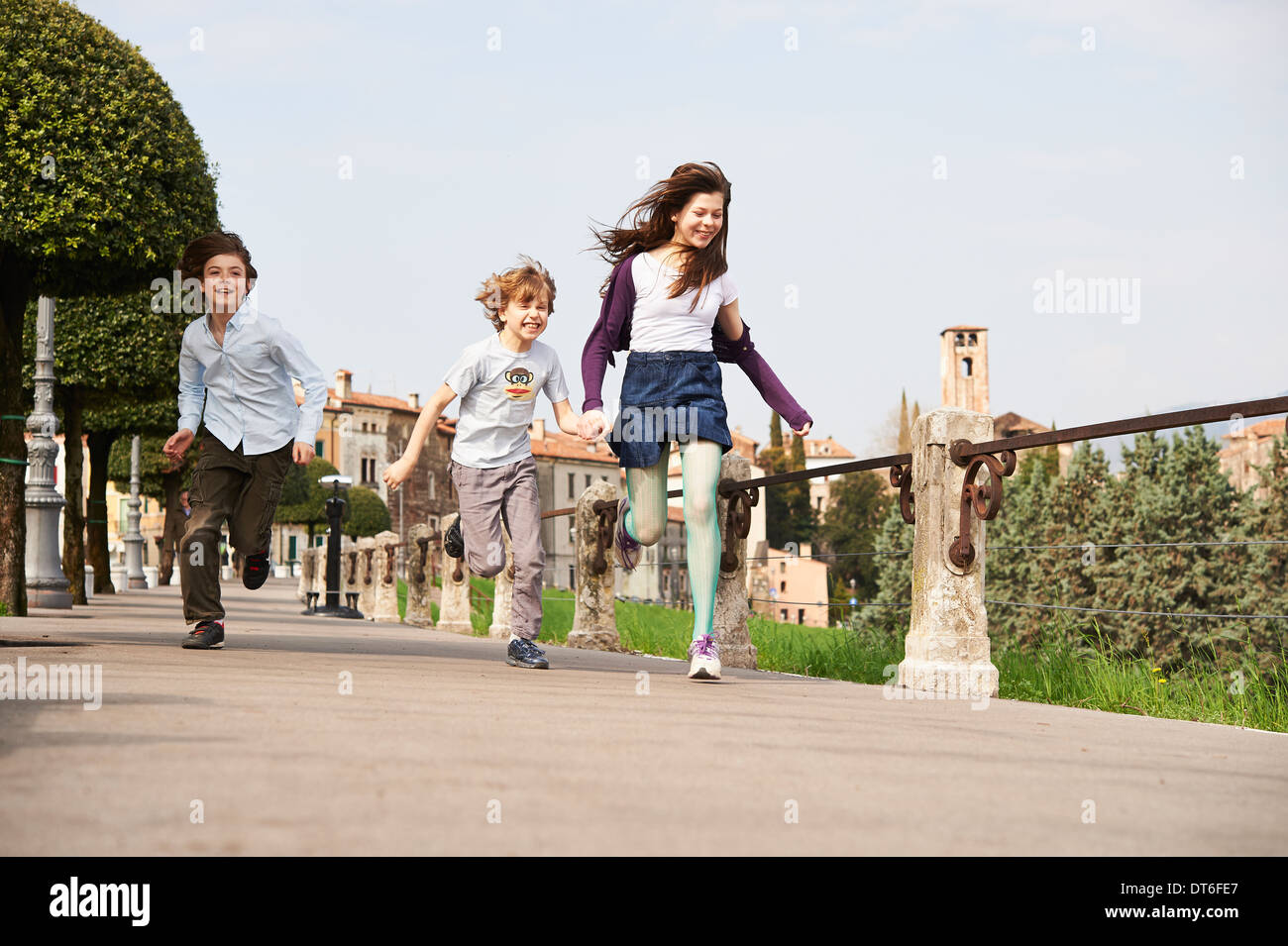 Young boys and older sister running through park, Province of Venice, Italy Stock Photo