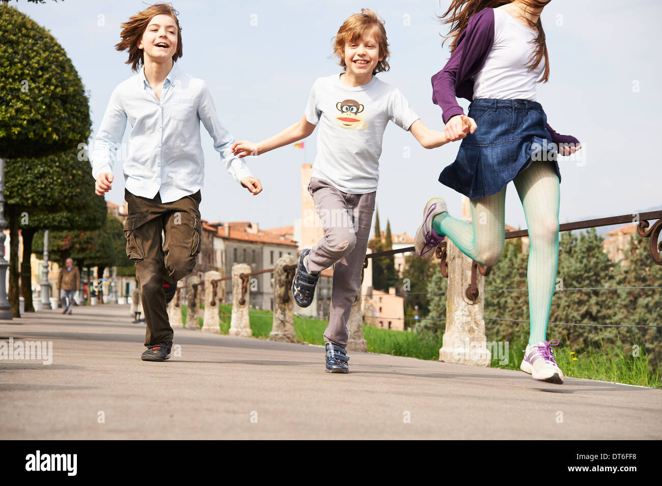 Sister and younger brothers running through park, Province of Venice, Italy Stock Photo