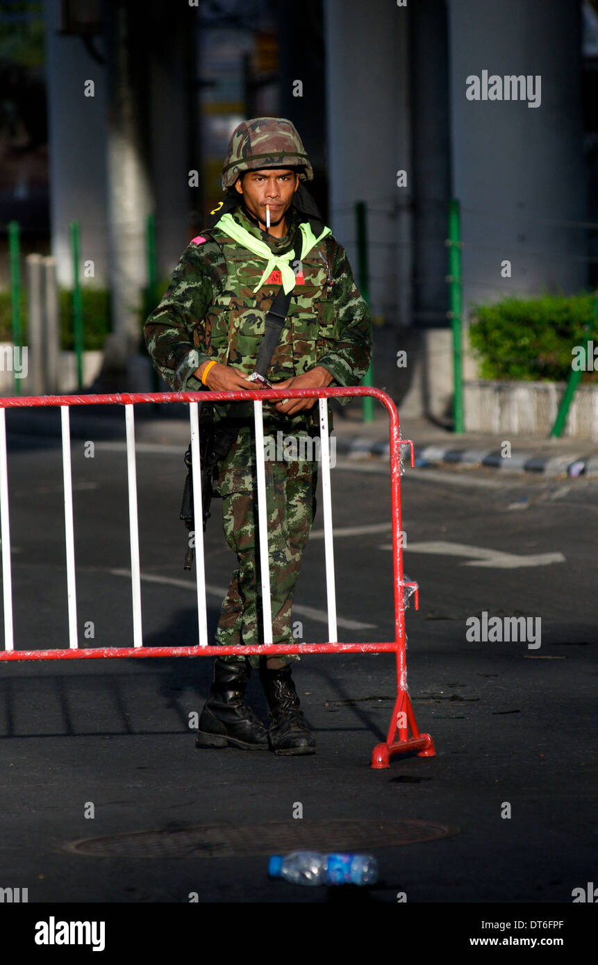 Thai military standing guard, cigarette in mouth, Red shirt protest, Ratchaprasong intersection, Rama 1 Road, Bangkok, Thailand. Stock Photo