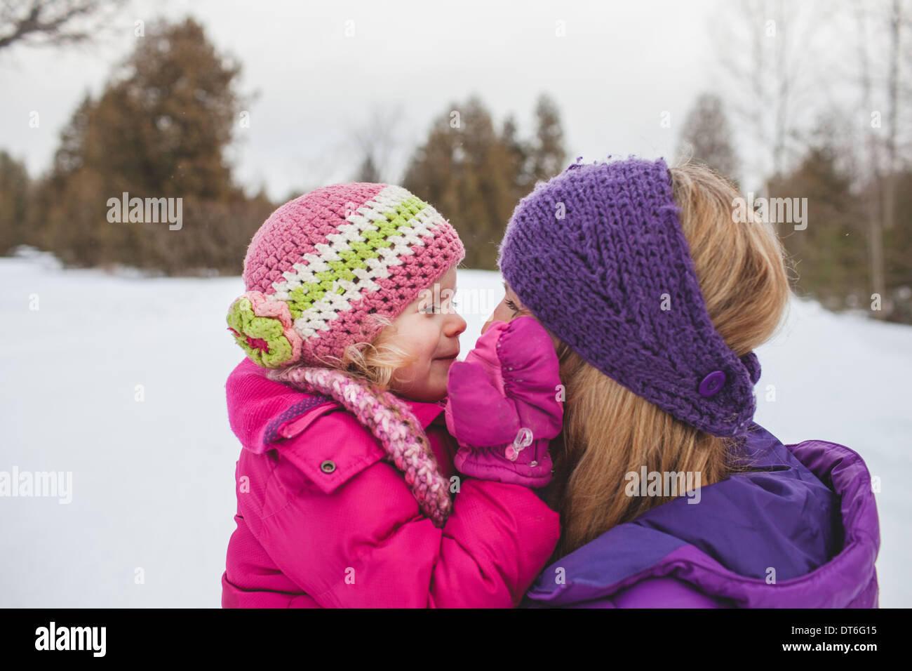 Mother and daughter wearing winter clothing, face to face in snow Stock Photo