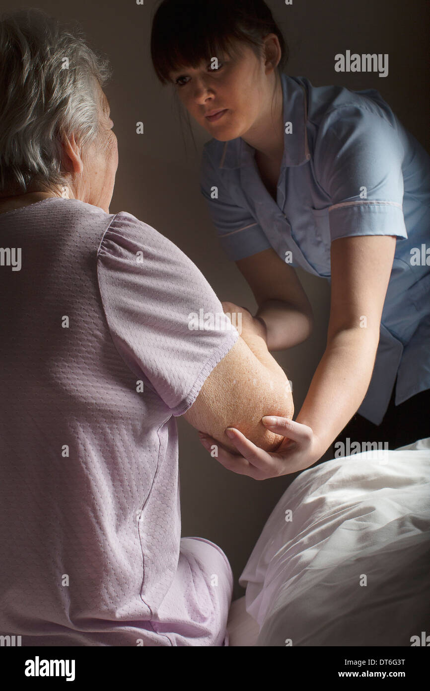 Personal care assistant helping senior woman to get up Stock Photo