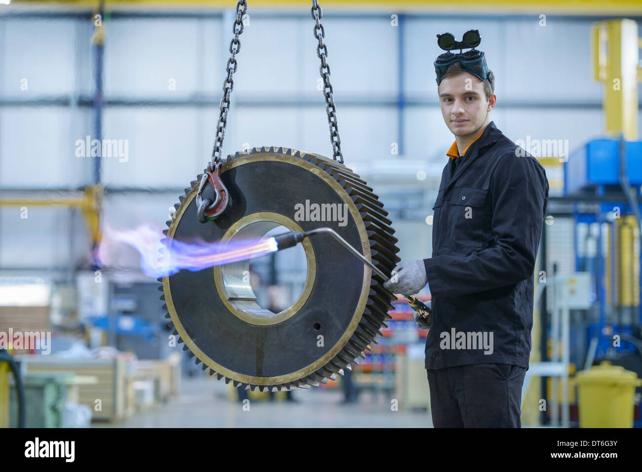 Portrait of engineer heat treating industrial gear in factory Stock
