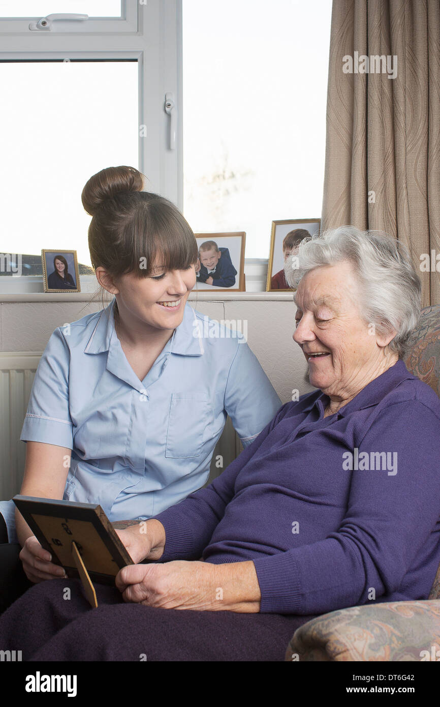 Personal care assistant looking at photograph with senior woman Stock