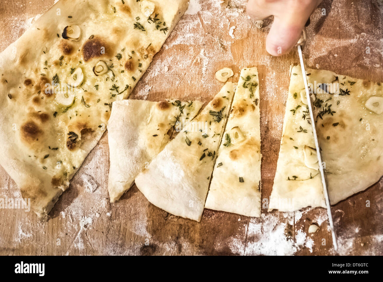 Chef's hand slicing pizza bread in commercial kitchen Stock Photo