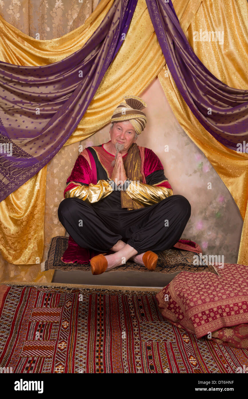 Sultan character greeting while sitting on a flying carpet Stock Photo