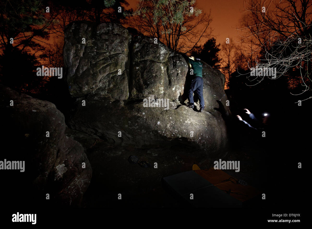 Climber climbs a boulder at night by torchlight in the Forest of