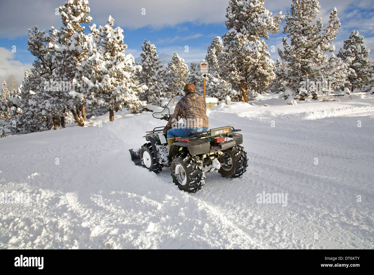 A senior citizen plows snow with an ATV, all terrain vehicle, after a major snow storm in central Oregon. Stock Photo