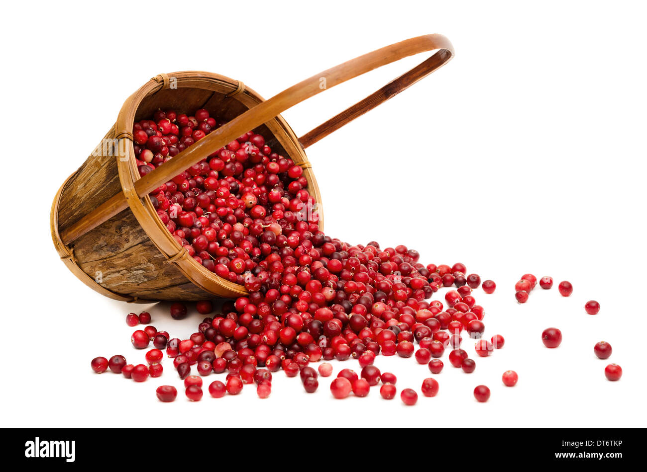Сranberries spilling from wooden basket, isolated on white background Stock Photo