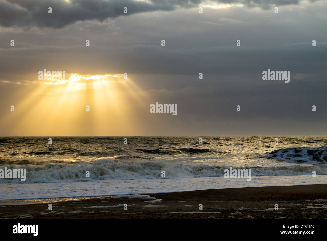 Crepuscular rays shine down on the ocean at sunrise. Stock Photo