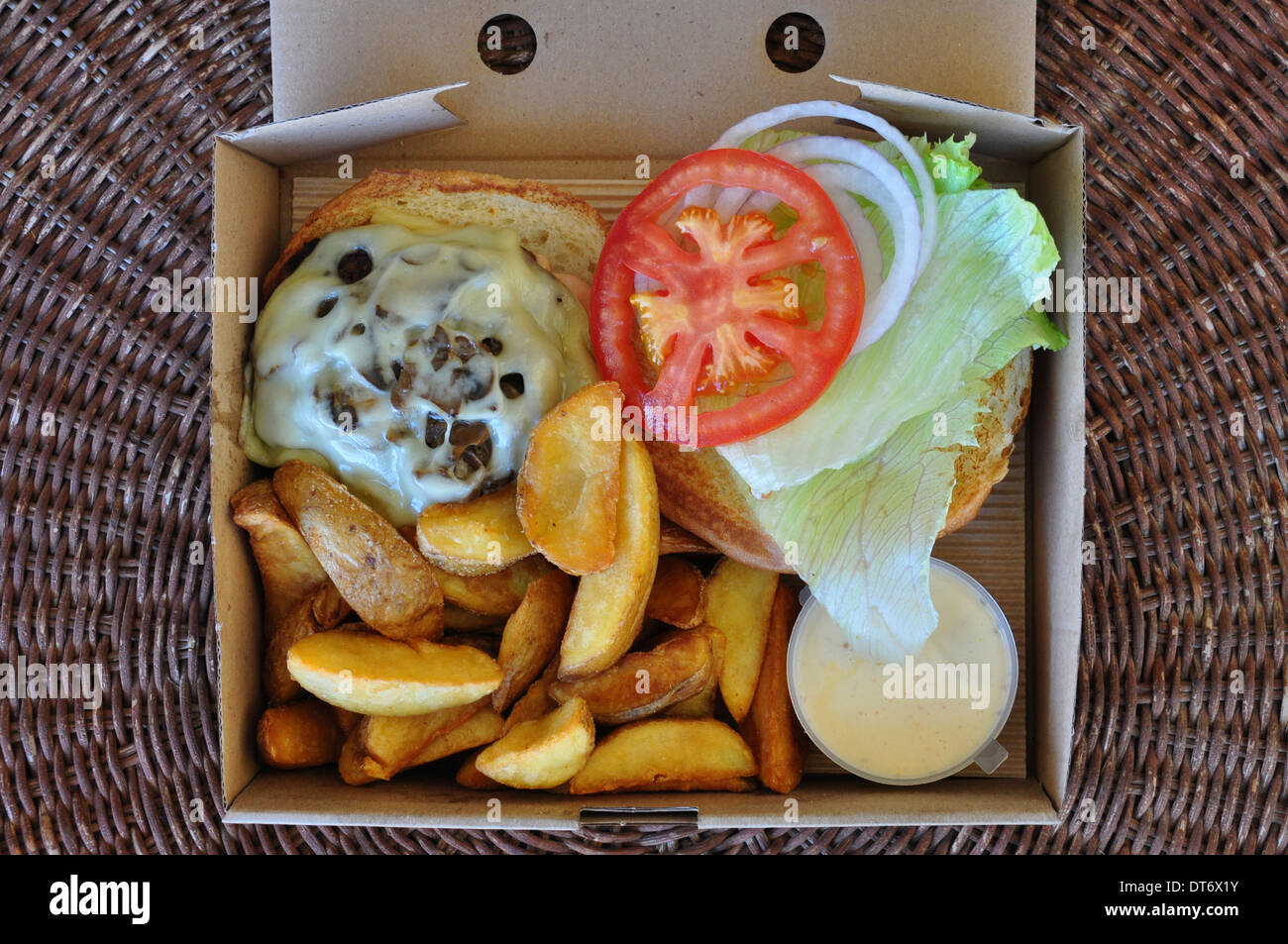 Burger with fries and melted cheese mushrooms. Takeaway food in packaging. Stock Photo