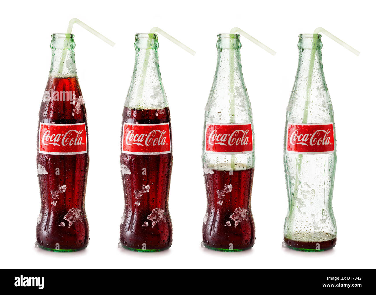 An icy cold bottle of coke progressively being drank from or emptied on a white background with a straw. Stock Photo