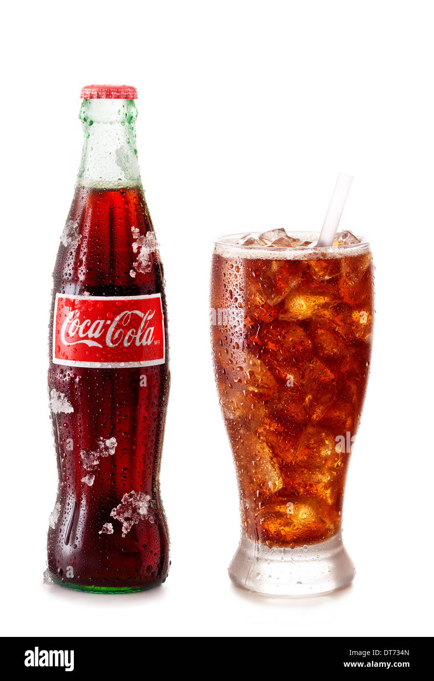 An icy cold bottle of coke with an icy cold glass of coke right next to it on a white background. Stock Photo
