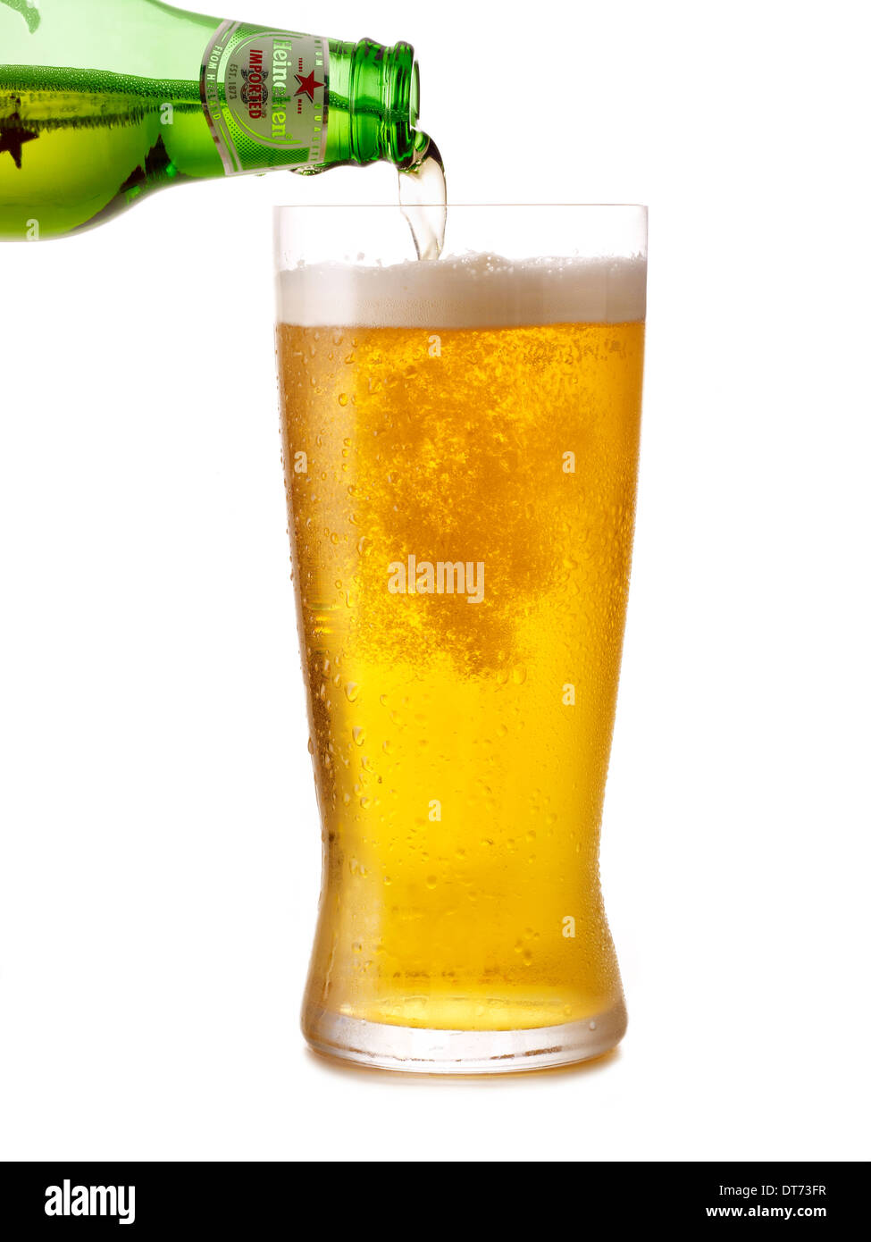 A bottle of Heineken beer being poured into a glass on a white background Stock Photo