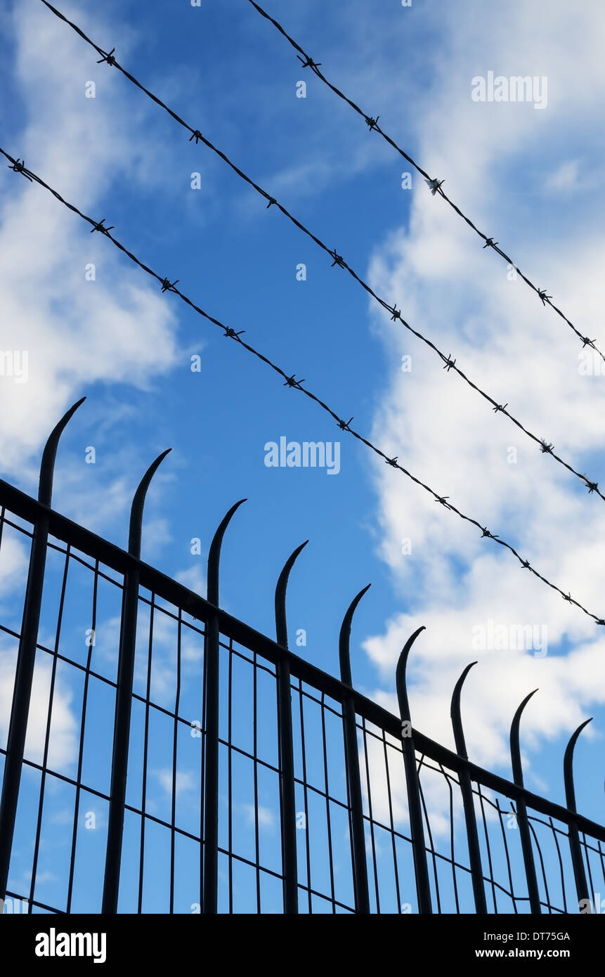 barbed wire and spiked mesh and bar fence silhouette with sky background Stock Photo