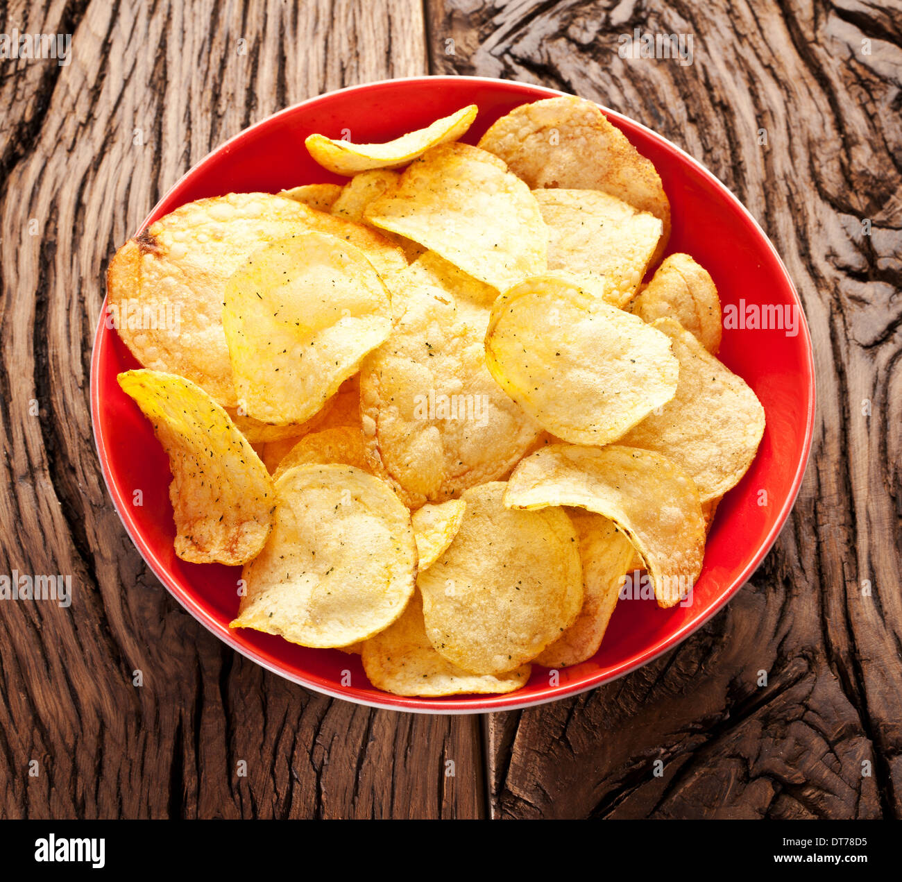 Potato chips in a bowl on a wooden table. Stock Photo