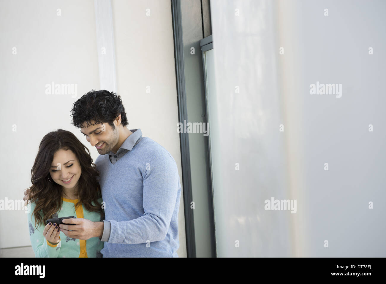 Urban Lifestyle. A young couple, man and woman side by side, looking at a mobile phone. Stock Photo