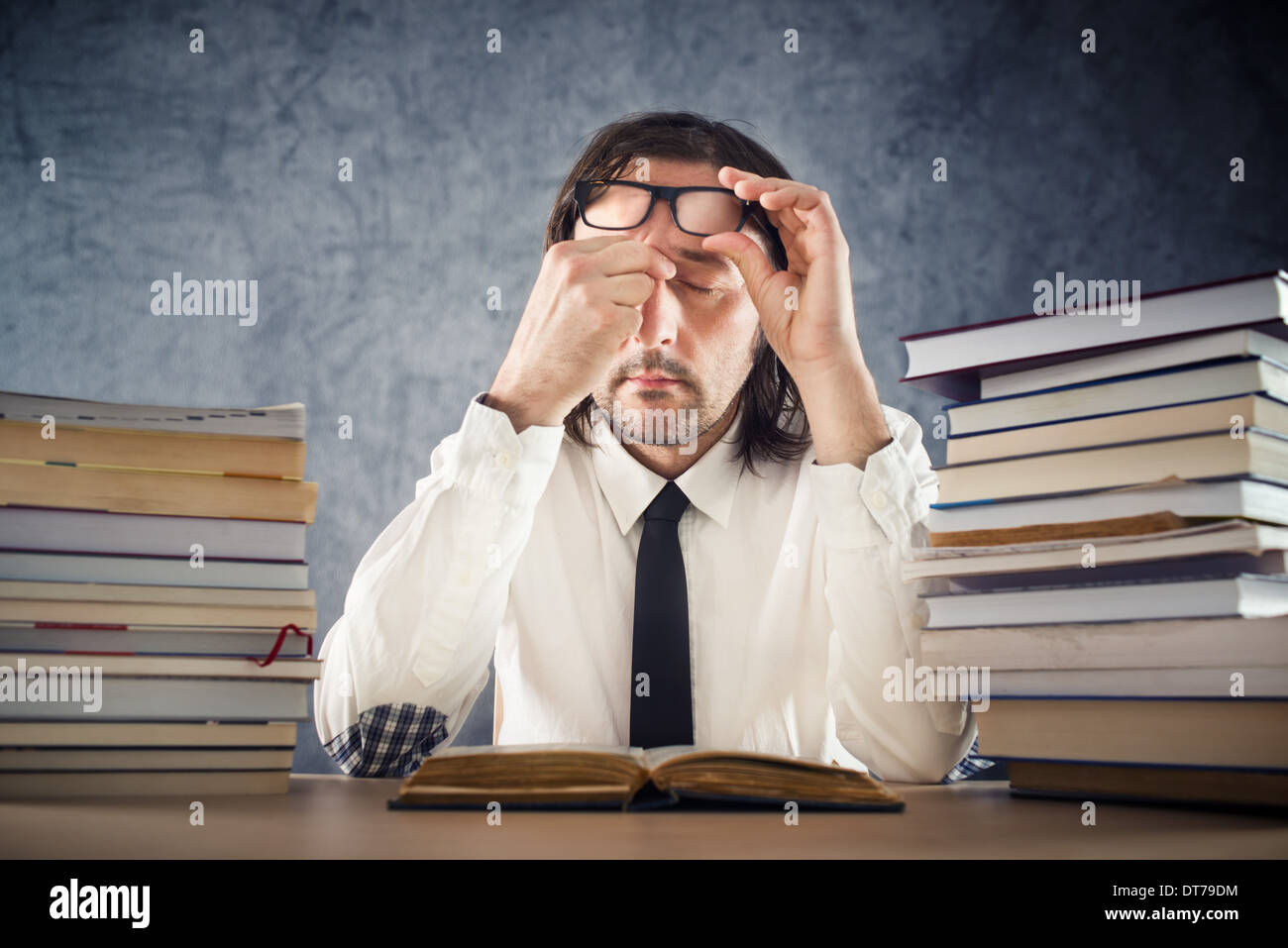 Exhausted man reading books at office desk Stock Photo
