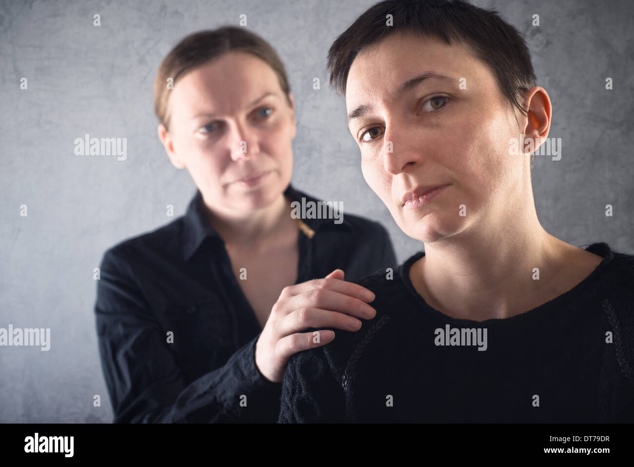 Comforting friend. Woman consoling her sad friend with hand on shoulder. Stock Photo