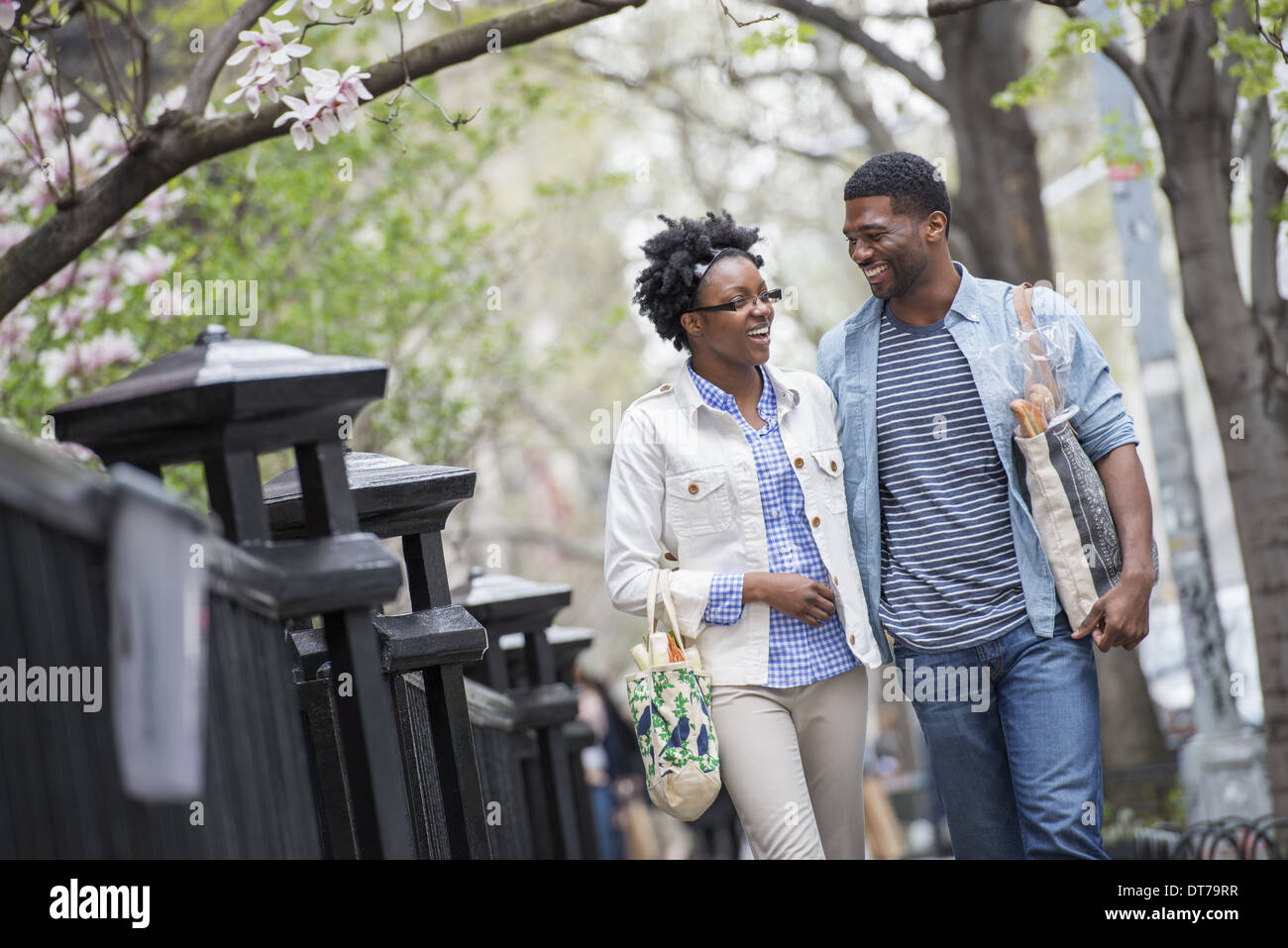 A couple walking in the park side by side carrying shopping bags. Stock Photo