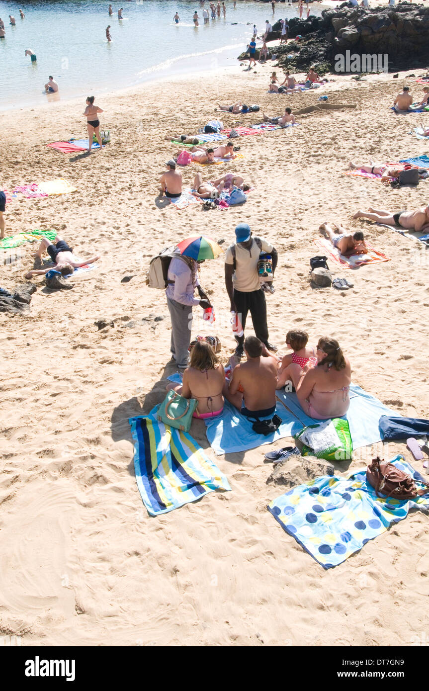 beach hawkers African migrants immigrants selling sunglasses to tourist  on a beach in lanazrote entrepreneurship  entrepreneurs Stock Photo