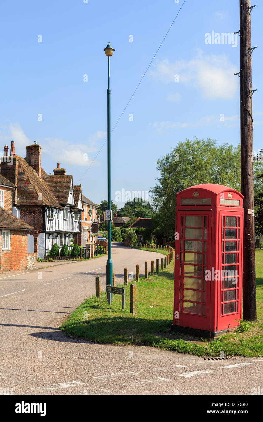 Traditional old red telephone box and telegraph pole on a village green in Chartham, Kent, England, UK, Britain Stock Photo
