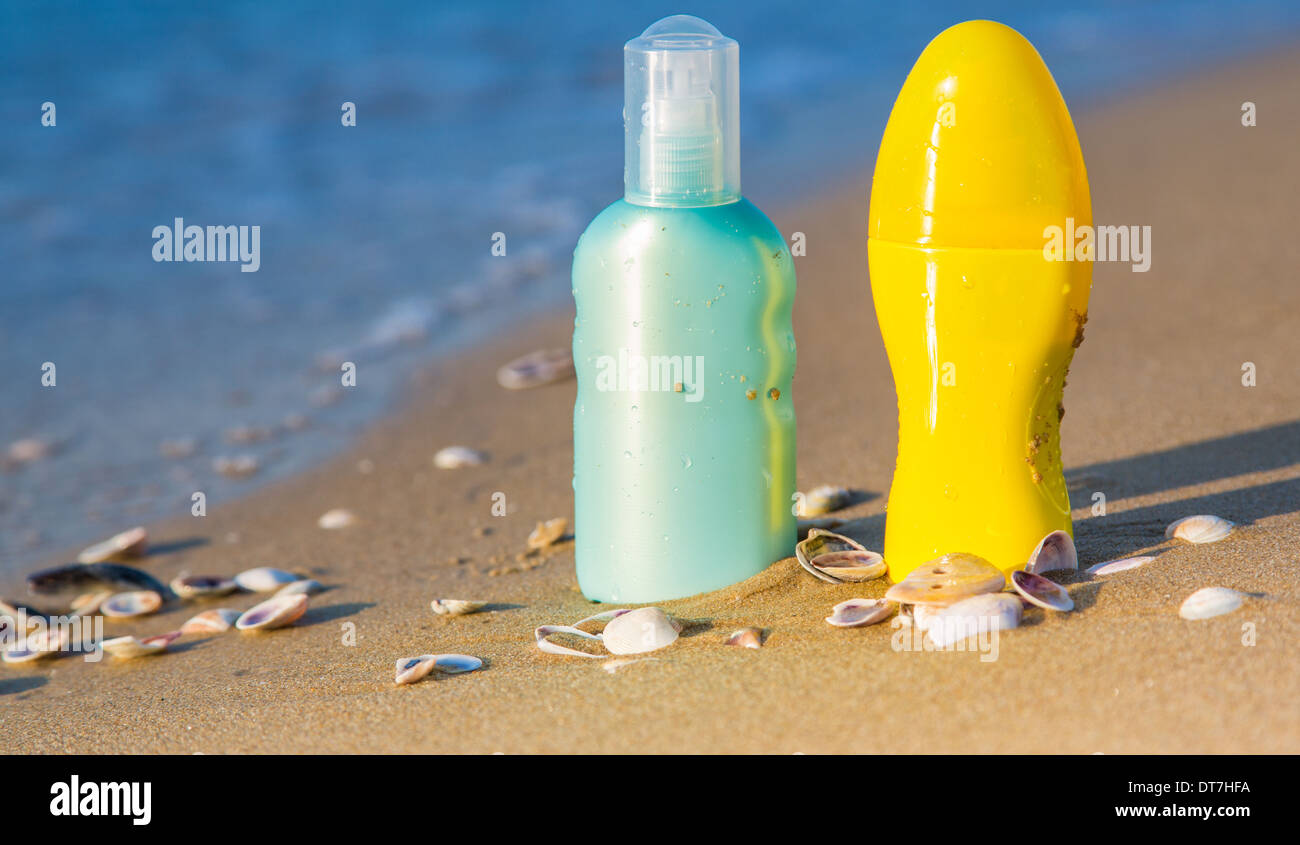 Sun protection creams on a seashore, sandy beach and sea water Stock