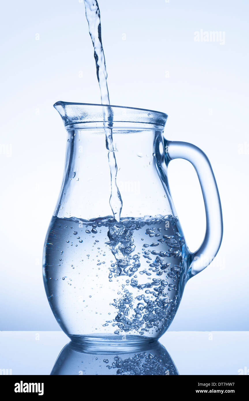 Flowing water in a jug on blue background Stock Photo