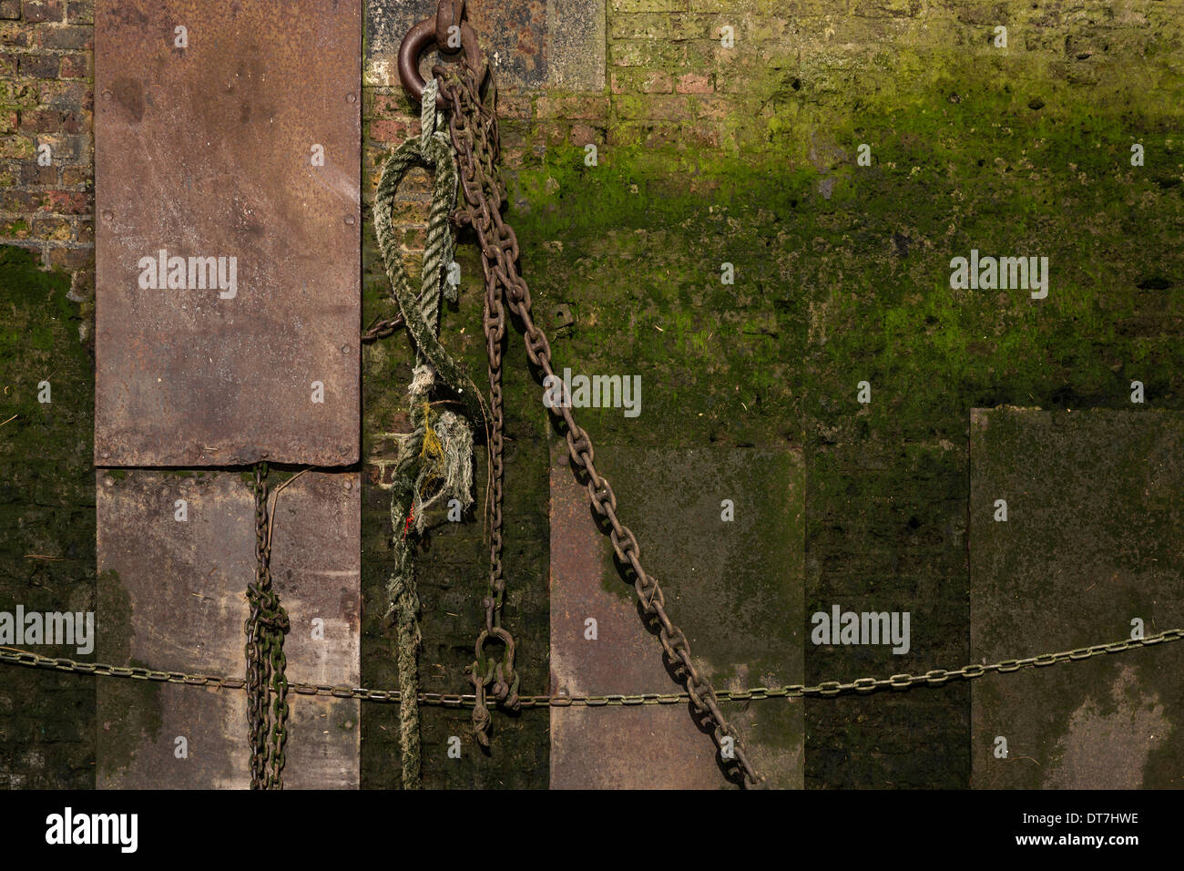 An old wall on the Thames foreshore with hanging chains and rope. Stock Photo