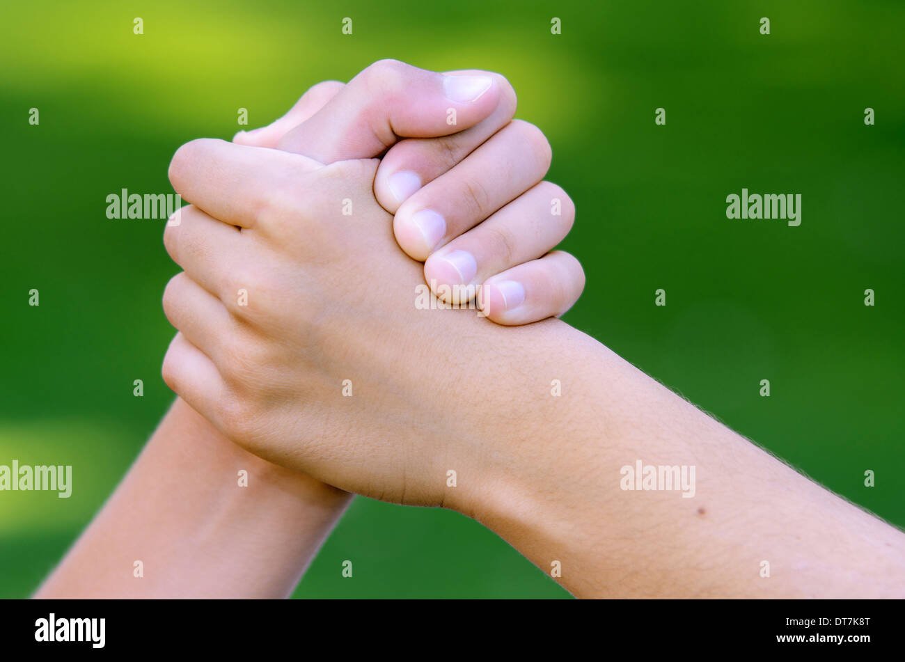 Cool handshake between two friends against green background Stock Photo