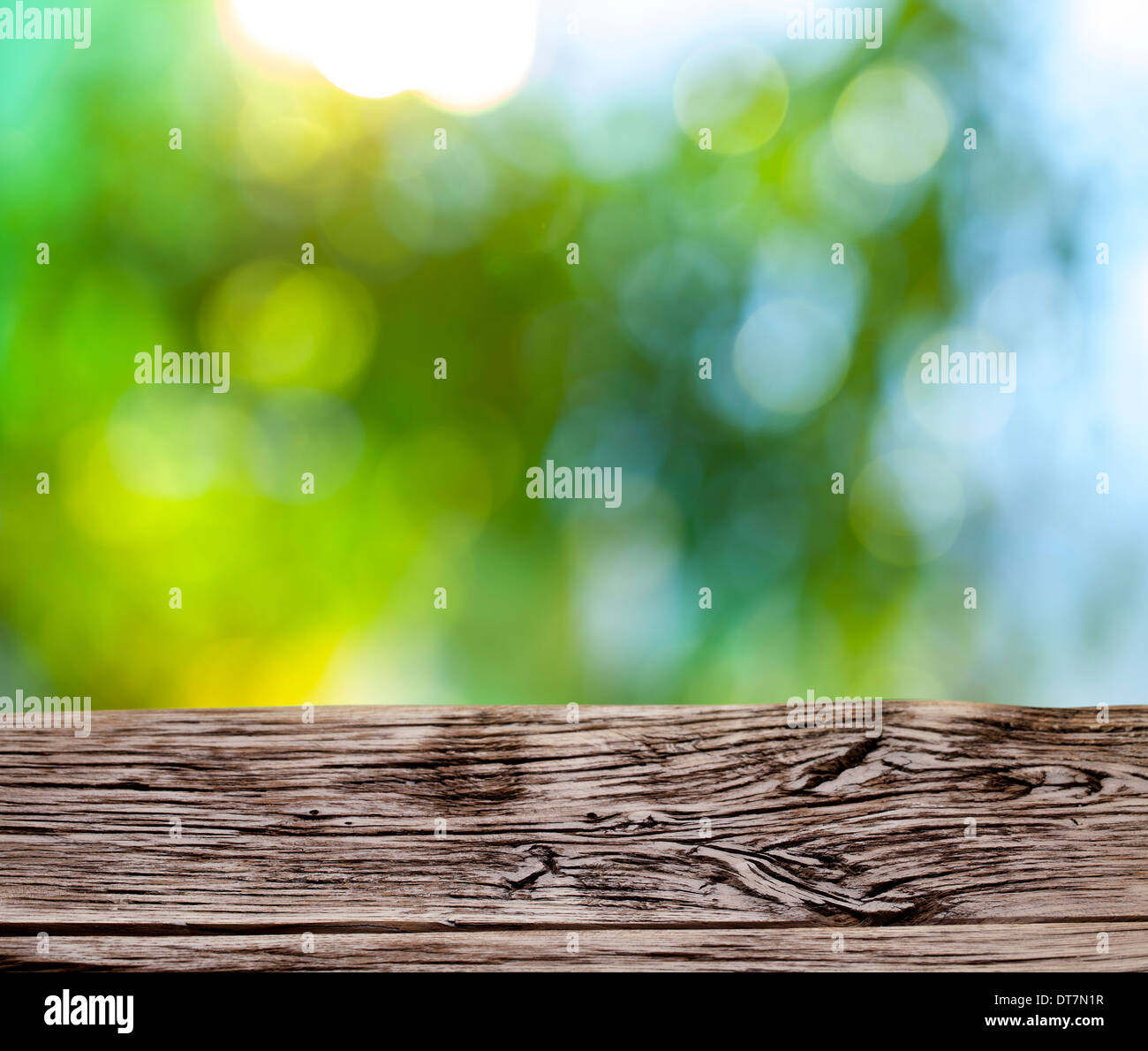Blurred nature background. In foreground the old wooden table. Stock Photo