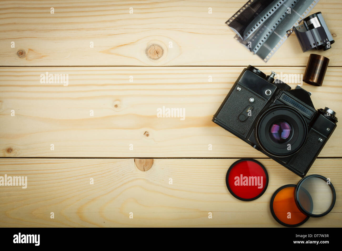 Old retro camera and film roll on wooden boards. Focus on camera. Abstract background Stock Photo