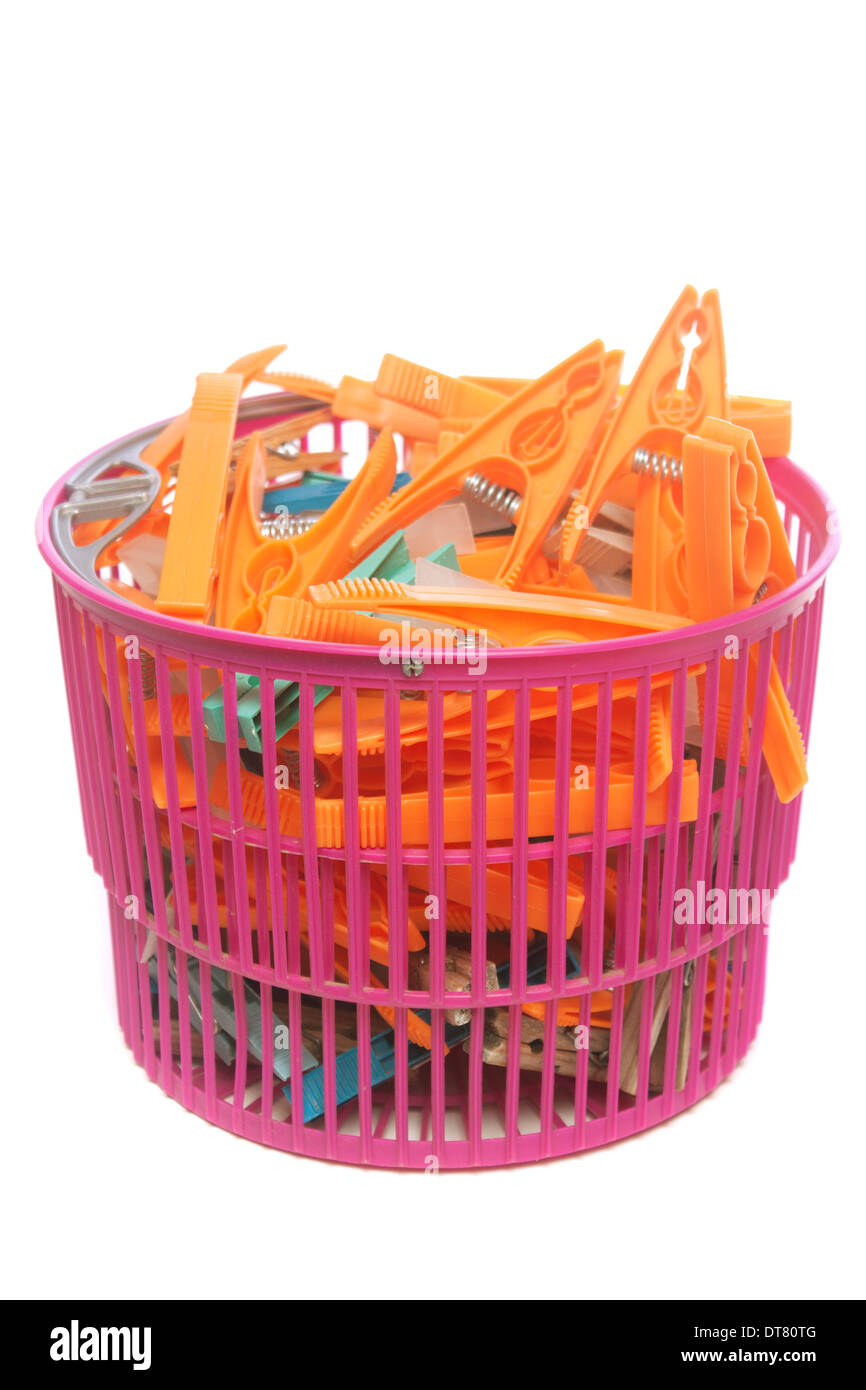 Colored clothes pegs in plastic basket isolated over white background Stock Photo