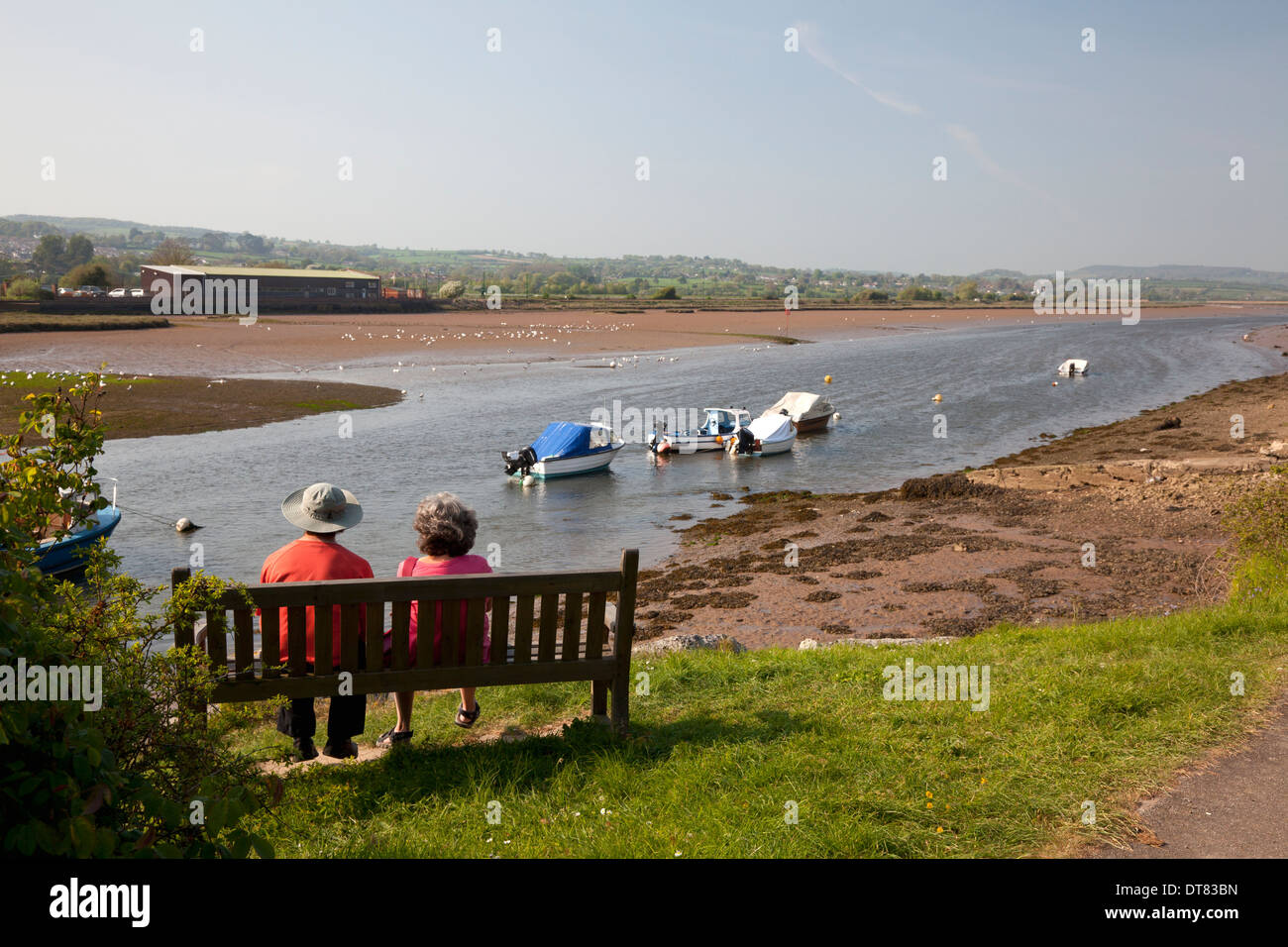 Couple sitting on a bench beside the Axe Estuary at Axmouth, Devon Stock Photo