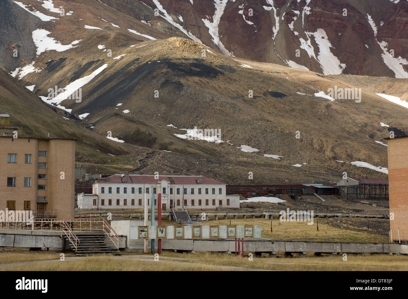 Abandoned civic buildings with looming cliffs behind, at the deserted Soviet Russian mining settlement of Pyramiden, Spitsbergen, Svalbard Archipelago, Norway Stock Photo