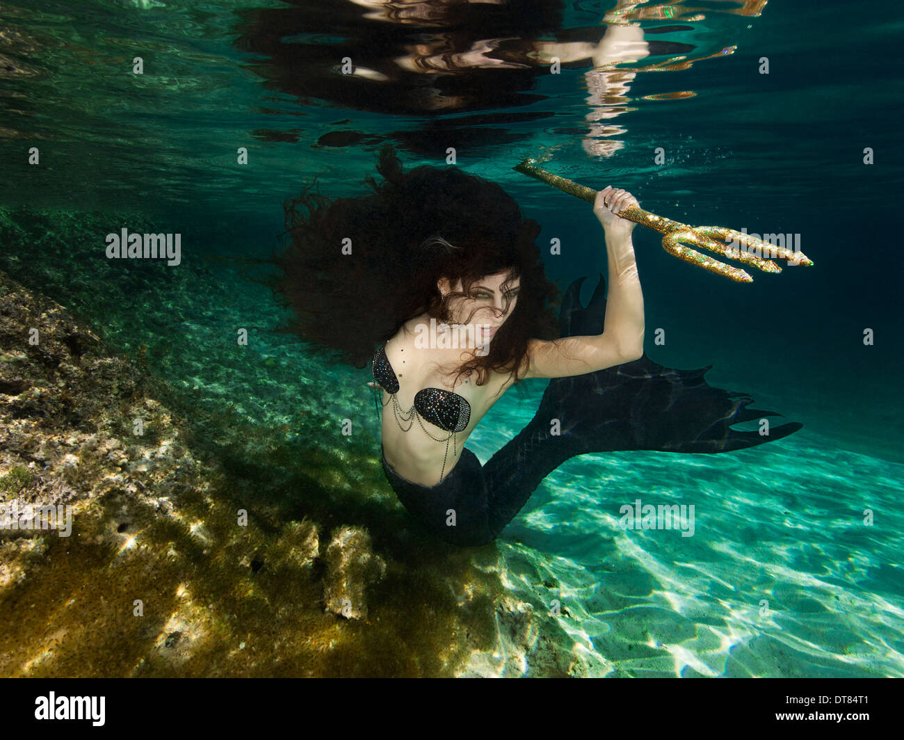 Evil hunter mermaid about to spear something wit her trident, off Bahamas Islands. Stock Photo