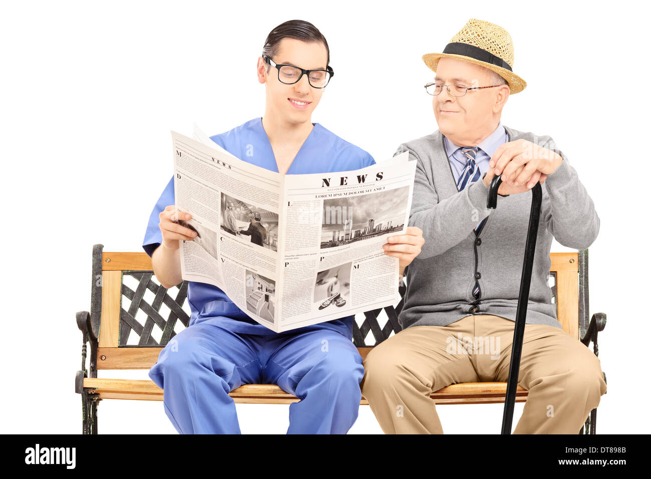 Male nurse reading a newspaper to an elderly gentleman seated on bench Stock Photo
