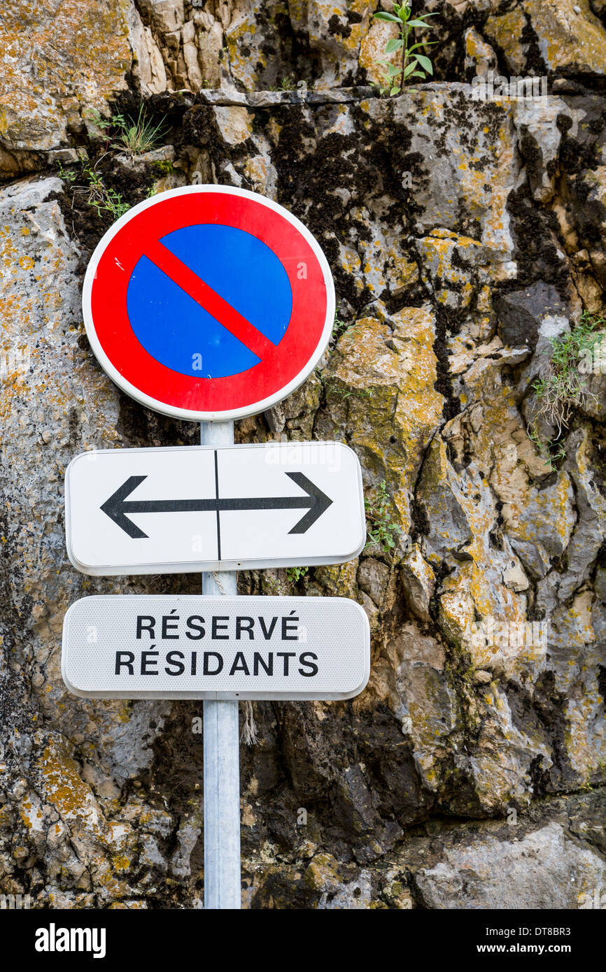 No parking sign in France by a stone wall restricted for residents