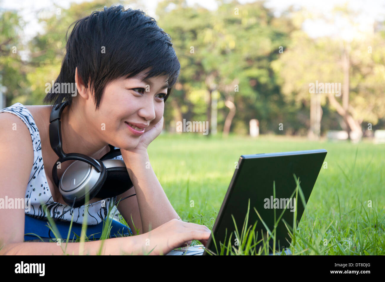 Asian lady using computer in a field Stock Photo - Alamy