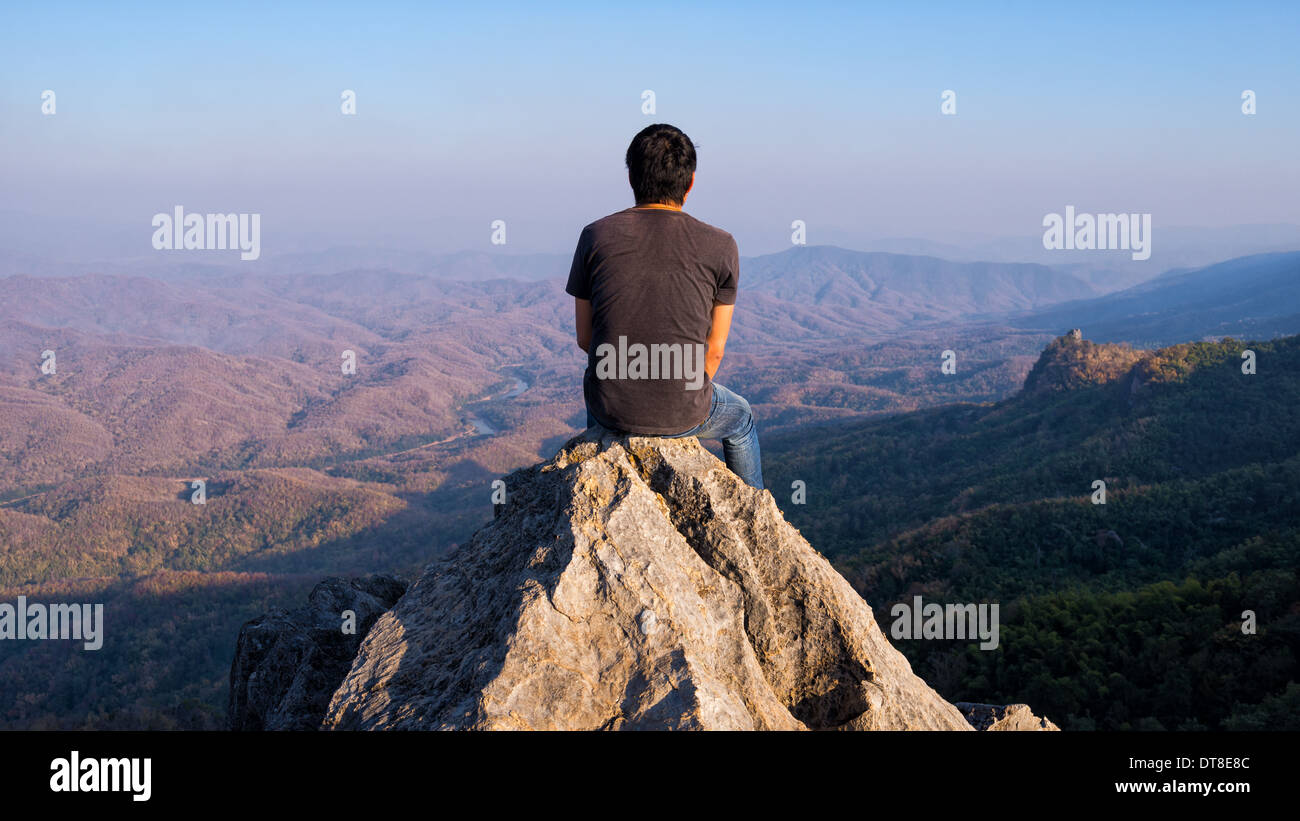 man sitting on stone top of high mountain Stock Photo - Alamy