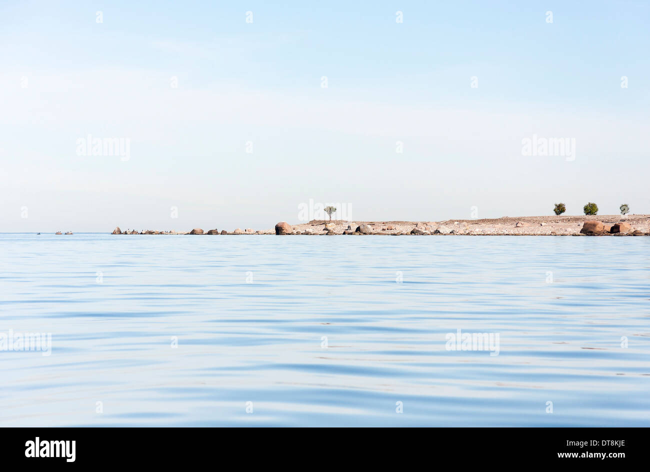Tail of an island in sea and few single trees growing on it Stock Photo