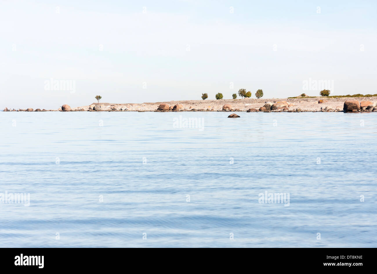 Tail of an island in sea and few single trees growing on it Stock Photo