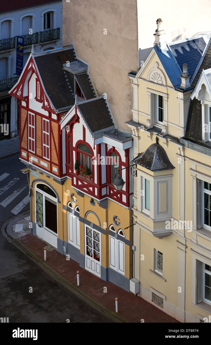 Tiny vintage chalet built onto big residential blocks (Vichy, France). Big building vs little tiny house. Stock Photo