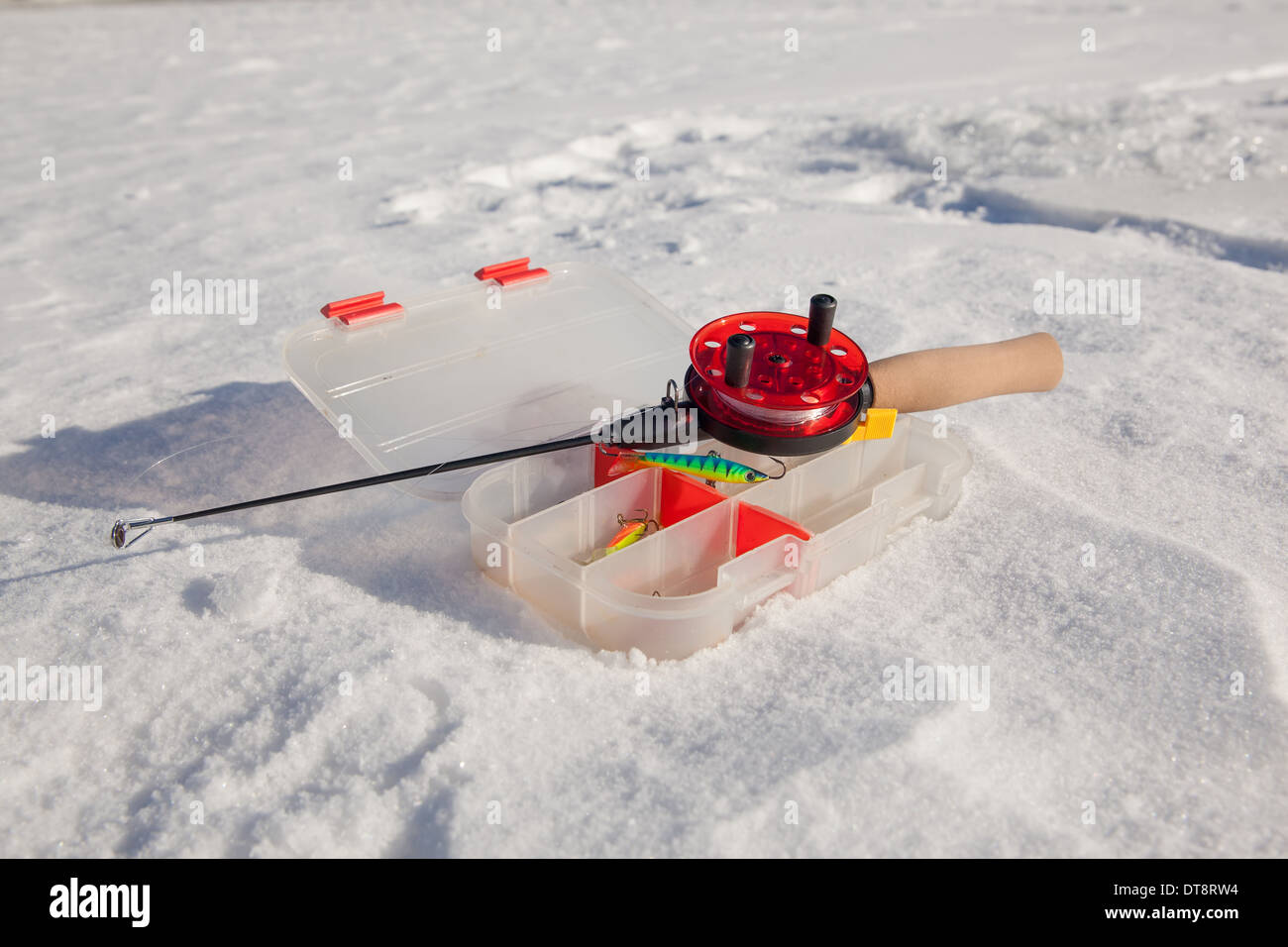 Hand ice auger and tip-up ice fishing rod at frozen lake at Winter