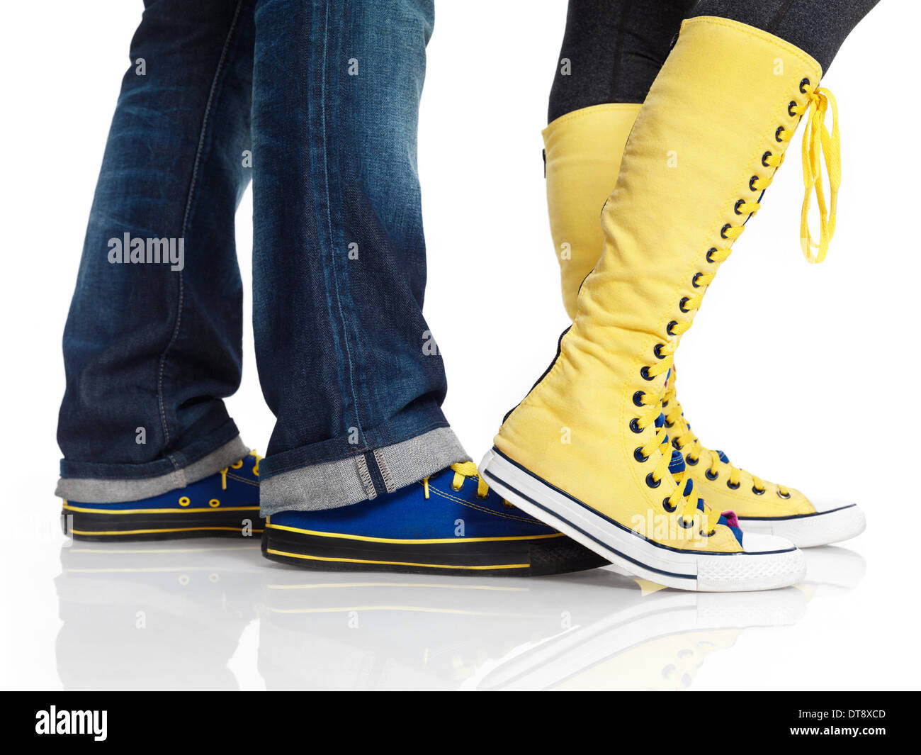 Closeup of woman and man legs in colorful blue and yellow trainers shoes isolated on white background Stock Photo