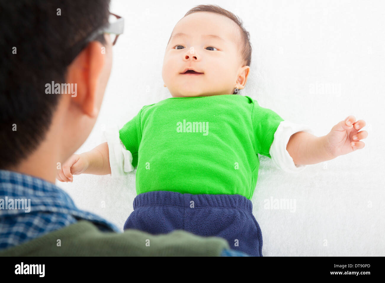 Young happy father playing with baby lying in bed at home Stock Photo
