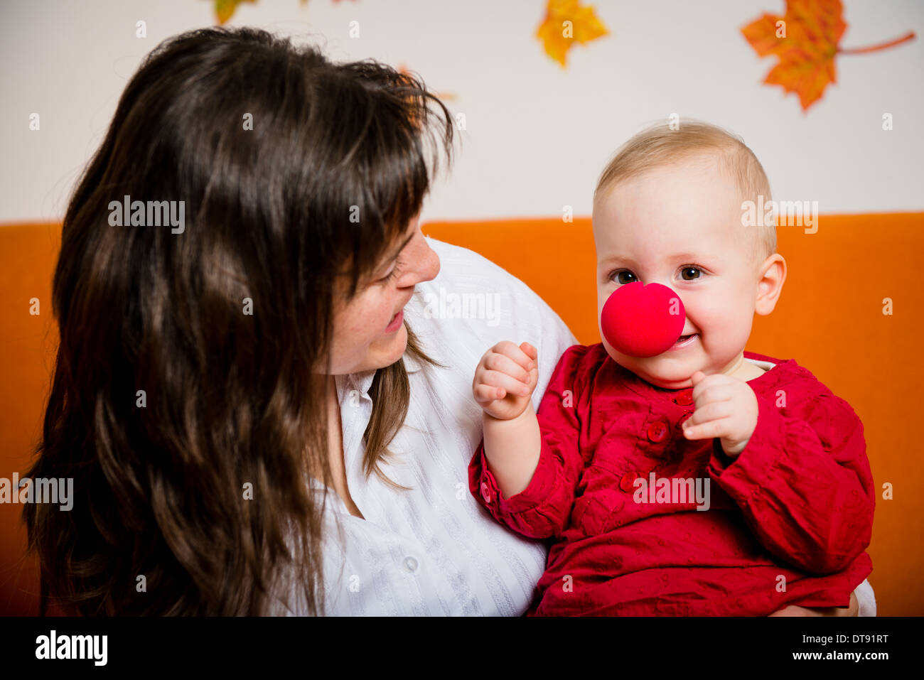 Mother playing with her smiling baby - child has red clown nose Stock Photo